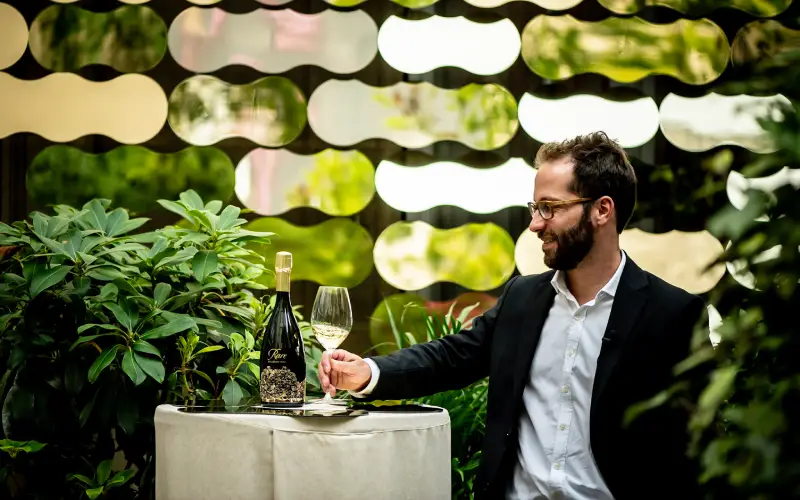 Émilien Boutillat, chef de caves de Rare Champagne, avec le millésime 2013, devant l'œuvre d'Arnaud Lapierre. Crédit : Anthony Dorfmann.